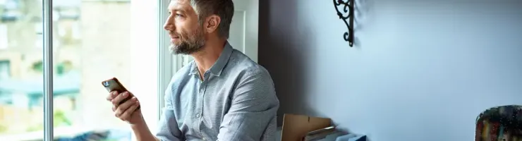 Un homme discute avec une personne via son téléphone portable dans un salon lumineux.