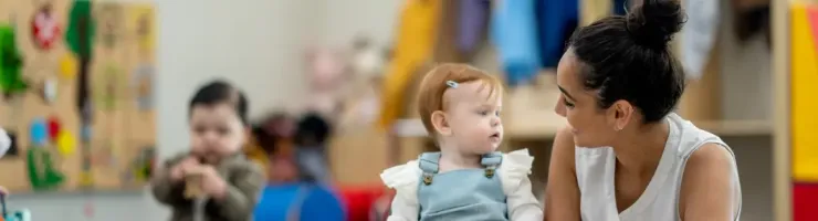 Une agent territorial spécialisée des écoles maternelles aide un bébé à jouer .