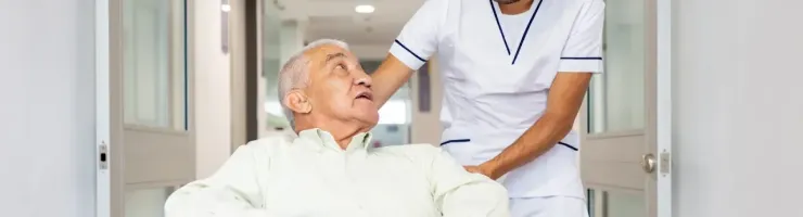 Un infirmier pousse le fauteuil roulant d'une personne âgée dans un hôpital.