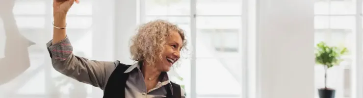 Une institrice souriante prêt à écrire sur un tableau blanc. Elle regarde les élèves.