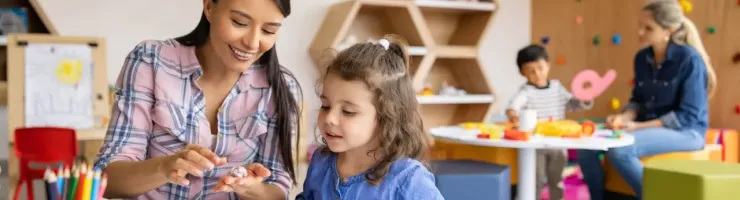 Une maitresse d'école montre à une élève comment faire de la pâte à modeler