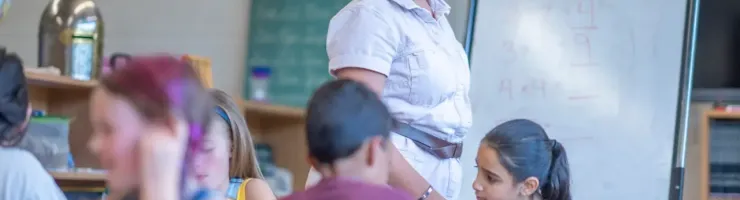 Une enseignante regarde ses élèves en train de travailler.