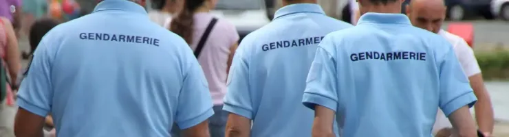 Trois gendarmes vus de dos en patrouille ou en inspection.