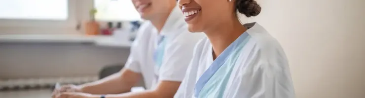 Deux professionnels de santé souriants sont assis à une table avec des verres d'eau.