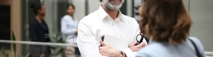 Homme en chemise blanche discutant avec une femme dans un hall moderne.