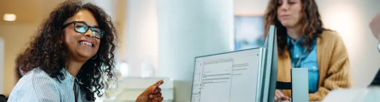 Une femme de mairie travaille à un bureau dans un espace moderne et accueille le public.
