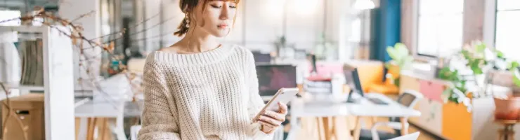 Femme regarde son téléphone et prend des notes