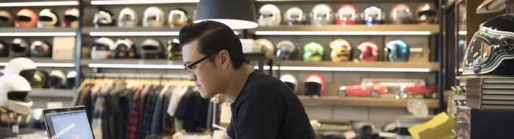 Un homme travaille sur son ordinateur portable. Il tient un magasin d'équipements de moto.