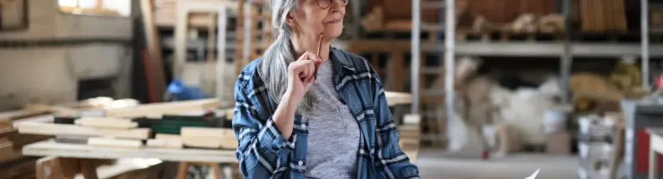 Une femme dans un atelier, tenant un document, concentrée sur son travail