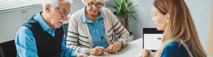 Couple âgé examine des documents avec une jeune femme à un bureau