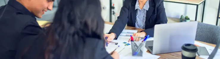 Trois personnes sont assises autour d'une table, regardant des documents.