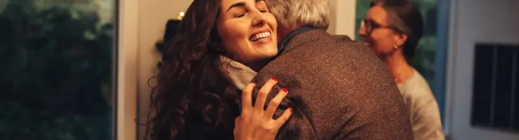 Une fille et son père se font un calin devant l'entrée de la maison.