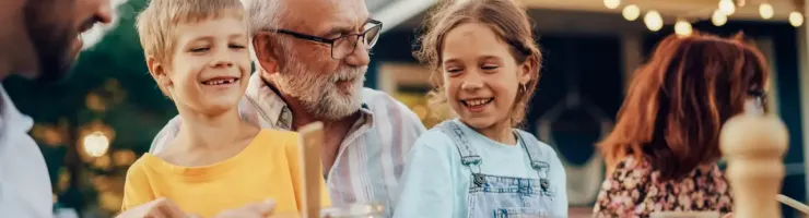 Famille heureuse réunie autour d'une table à l'extérieur, partageant un repas.
