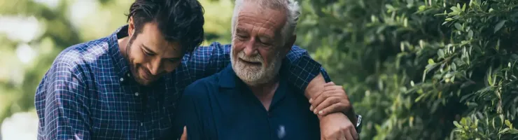 Un homme réconforte une personne âgée en plein air.