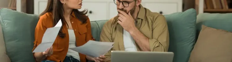 Couple assis sur un canapé examinant un contrat ensemble.