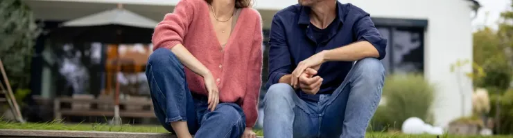 Couple assis sur des marches à l’extérieur, souriants, partageant une conversation.