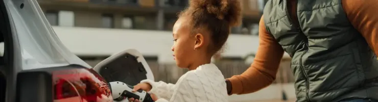 Un papa montre à sa petite fille comment recharger une voiture électrique