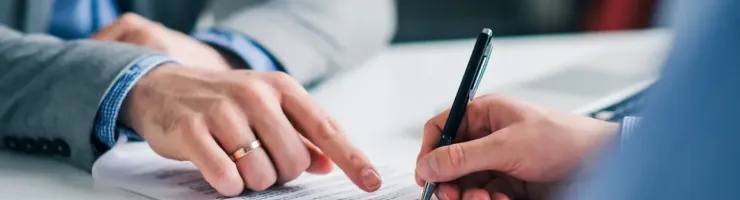 Une signature de contrat ou de document officiel est en cours, gros plan sur les mains.