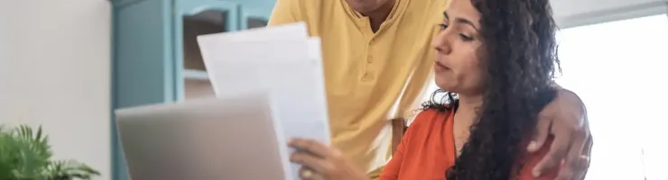 Un couple est en train de discuter sur des documents. Les personnes s'aident de leur ordinateur portable pour trouver des informations.