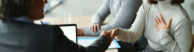 Un couple sert la main d'une conseillère bancaire