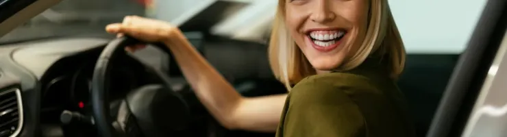Une femme sourit au volant de sa voiture, heureuse et confiante, prête à partir en déplacement.