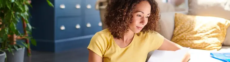 Femme d'âge moyen regarde des documents devant son canapé.