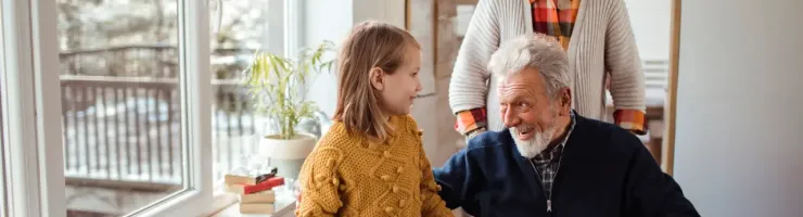 Couple âgé, dont un en chaise roulante, discute avec enfant.