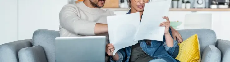 Homme et femme regardant des documents sur un canapé.