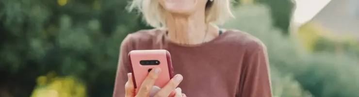 Femme senior utilise son smartphone en extérieur.