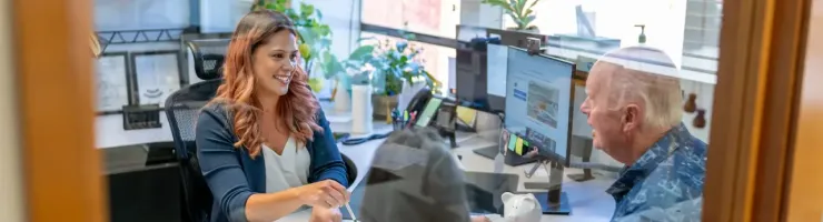 Une conseillère et un couple discutent autour d'une table dans un bureau moderne et lumineux.