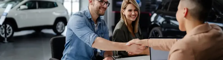 Un vendeur de voitures serre la main d'un client.
