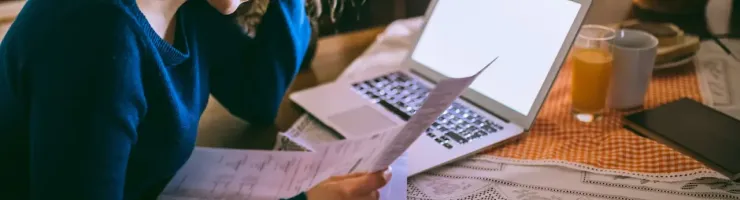 Jeune femme se tient la tête tout en consultant des documents