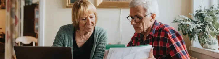 Une couple consulte des documents et s'aide d'un ordinateur portable.