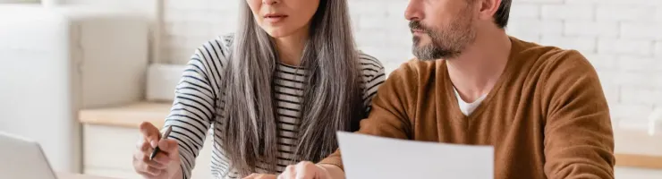 Un couple utilise un ordinateur portable et une calculatrice pour faire ses comptes à la maison.