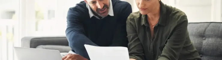 Couple en train de lire un document sur leur canapé.