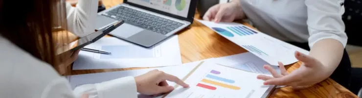 Deux personnes assises à une table examinent des graphiques et un ordinateur portable.