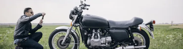 Une moto garée sur la route. Un motard prend une photo de sa moto.