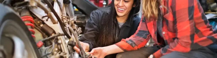 Deux femmes réparent une moto ensemble dans un atelier.