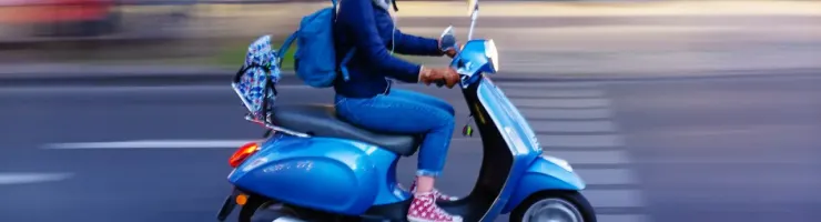 Personne roulant à vive allure sur un scooter bleu en ville.