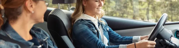 Une mère apprend à sa fille à conduire un véhicule.