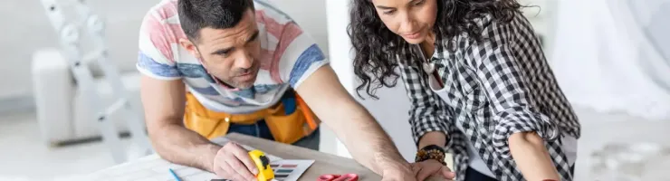 Homme et femme prennent des mesures sur plan d'architecte.