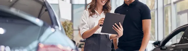 Une vendeuse de voitures parle à un client.