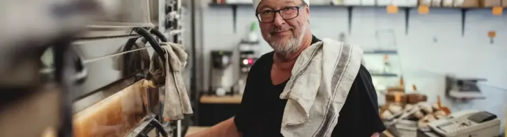 Un boulanger souriant attend que son pain cuit.