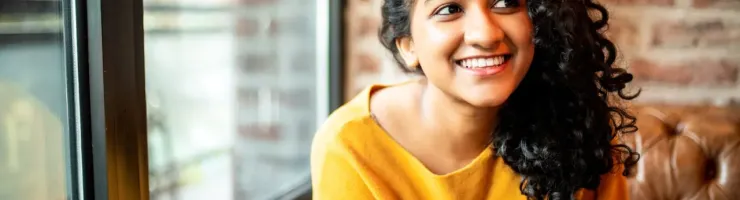 Femme aux cheveux bouclés tient un téléphone en regardant quelqu'un