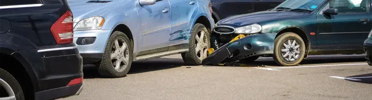 Deux voitures endommagées après un accident dans un parking, une SUV bleue et une berline verte.