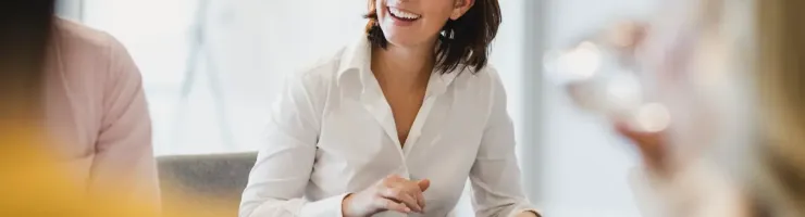 Une femme souriante en train de regarder l'orateur dans une salle de réunion.