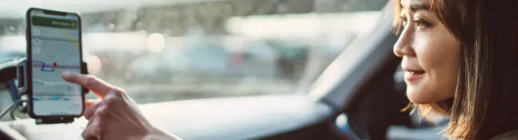 Une femme conduit une voiture en utilisant un smartphone pour la navigation.