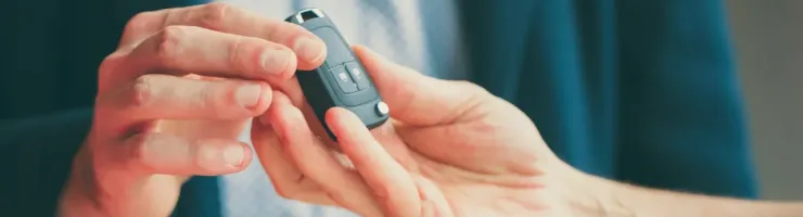 Une main tend une clé de voiture de type télécommande à une autre main.