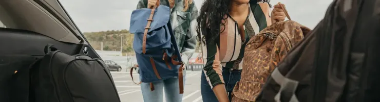 Deux femmes chargent leurs bagages dans le coffre d'une voiture.