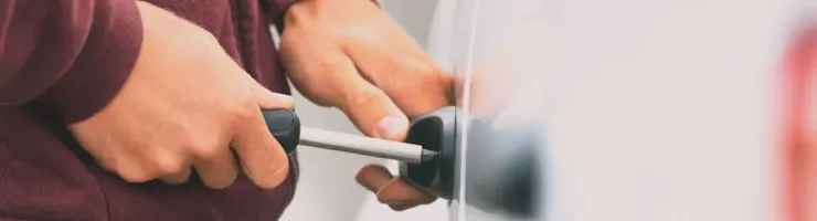 Les mains d'une personne insèrent une clé dans la serrure d'une portière de voiture blanche.